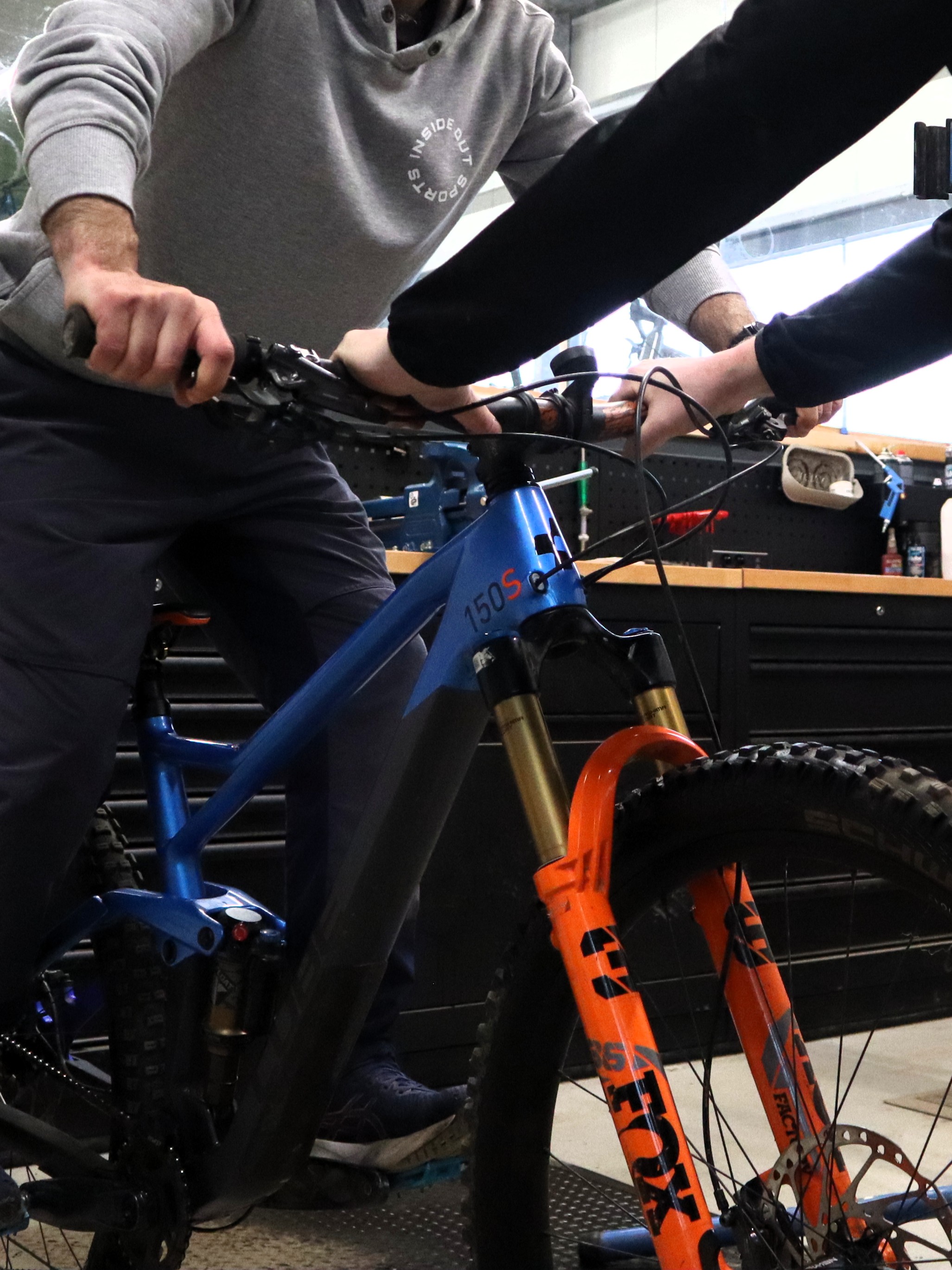 Buying advice at Indoor Mountainbike Almere — mechanic and customer looking over a full-suspension mountain bike with Fox Factory fork