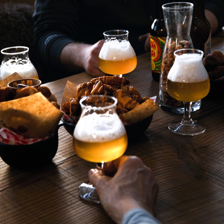 Speciaalbieren in tulpglazen met warme borrelsnacks en nootjes op een houten tafel